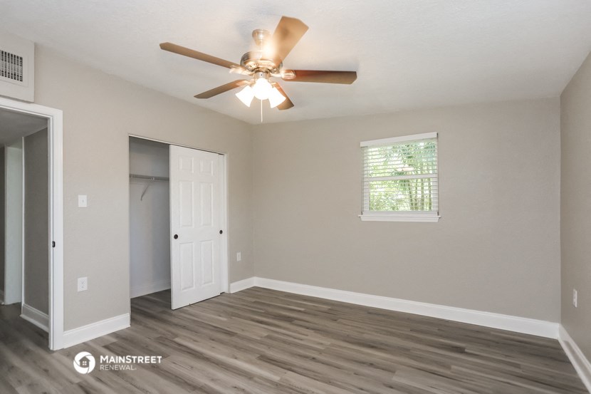 the spacious living room with ceiling fan and door to the closet