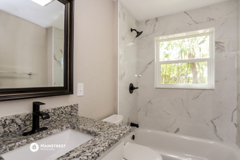 the master bathroom has a tub and a sink and a mirror