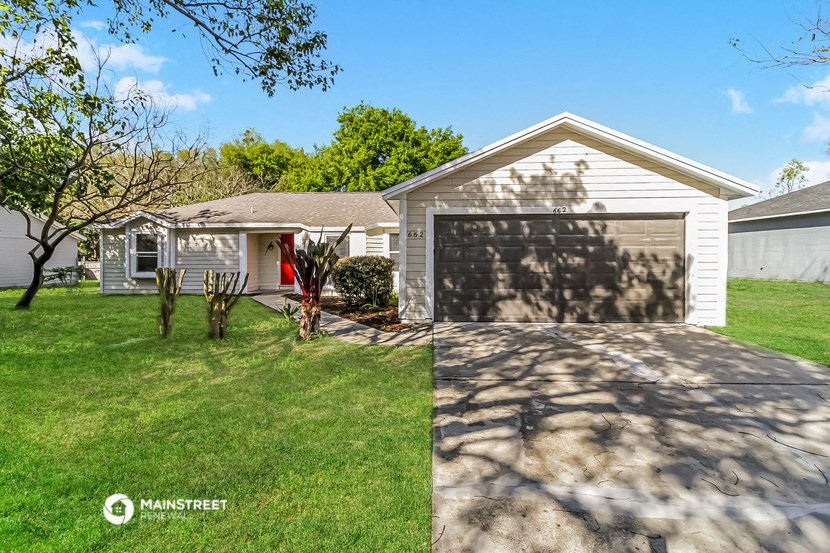 a white house with a garage door and a lawn