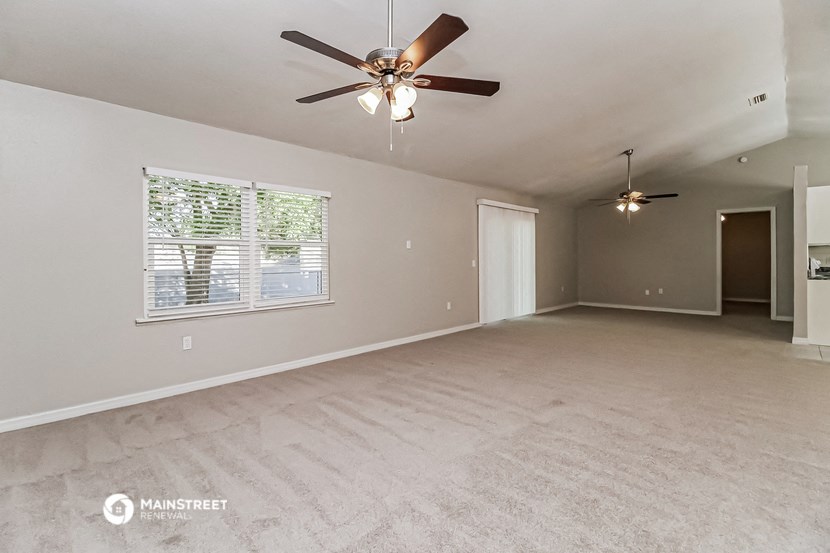 an empty living room with a ceiling fan and a window