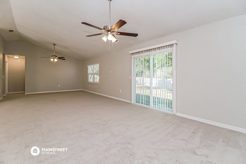 an empty living room with a ceiling fan and a window