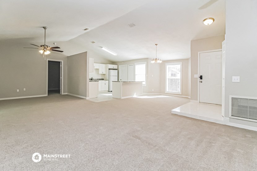 an empty living room and kitchen with a ceiling fan