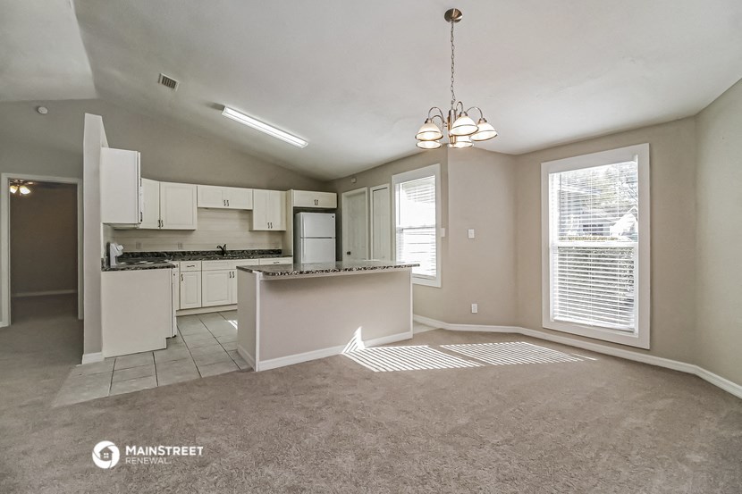 an empty living room and kitchen with a large window