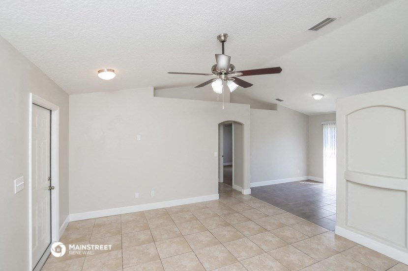 the spacious living room with ceiling fan and tile flooring