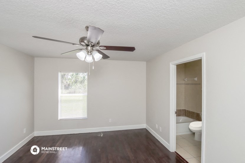 an empty room with a ceiling fan and a bathroom
