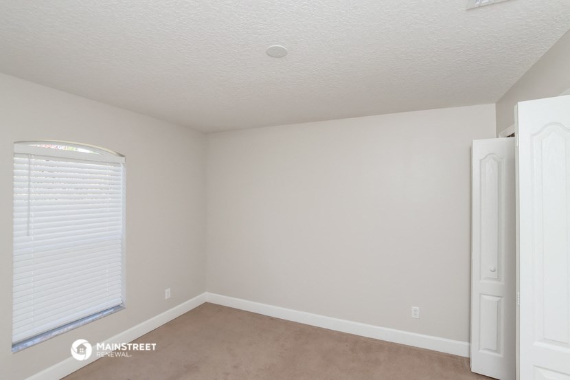 a bedroom with white walls and a window and a white door