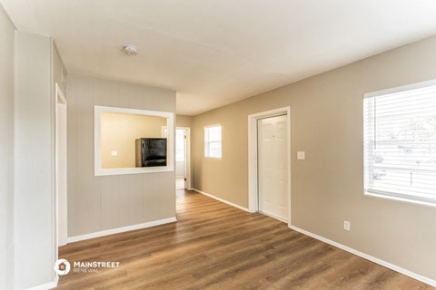 the living room and dining room of an apartment with a tv