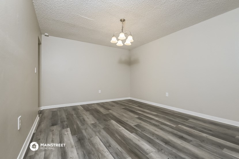 the living room of an apartment with wood flooring and a light fixture