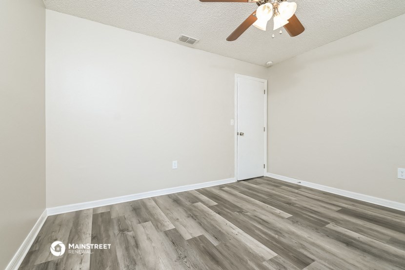 a bedroom with white walls and wood flooring and a ceiling fan