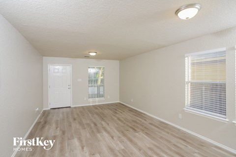 a spacious living room with wood flooring and a white door