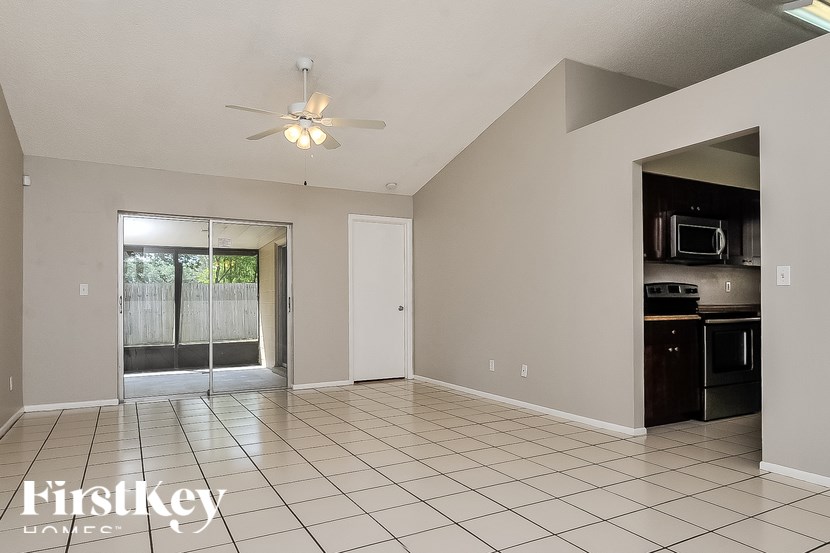A spacious living room with a kitchen area in the back.