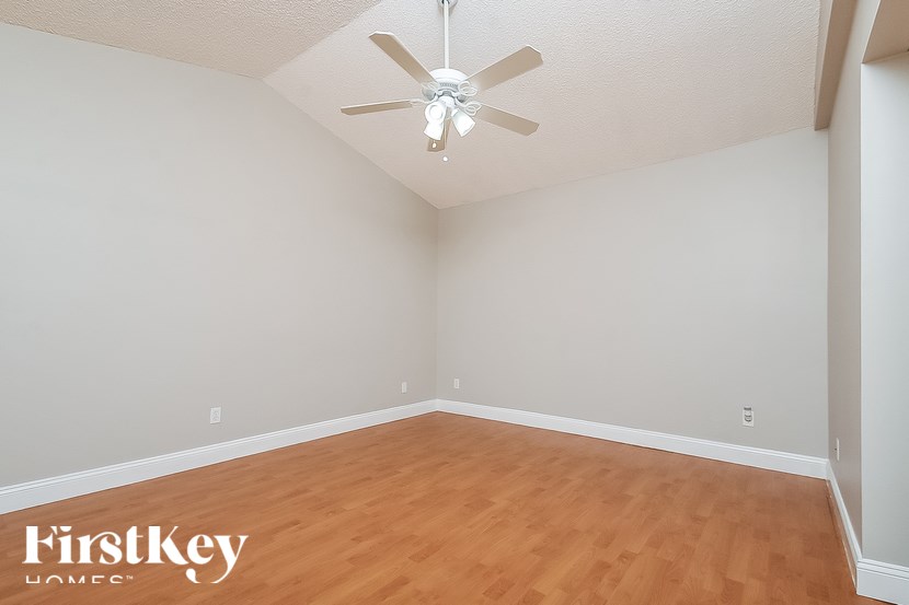 A room with a ceiling fan and wooden flooring.