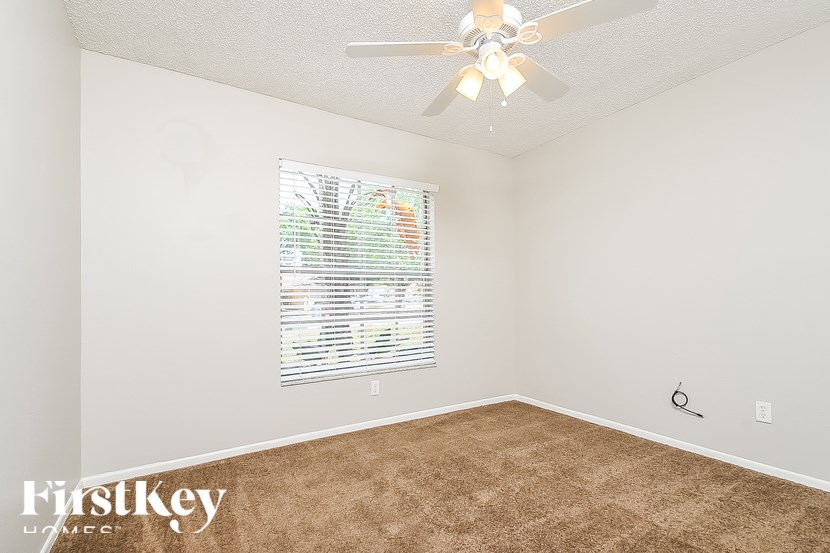A room with a ceiling fan and a window with blinds.