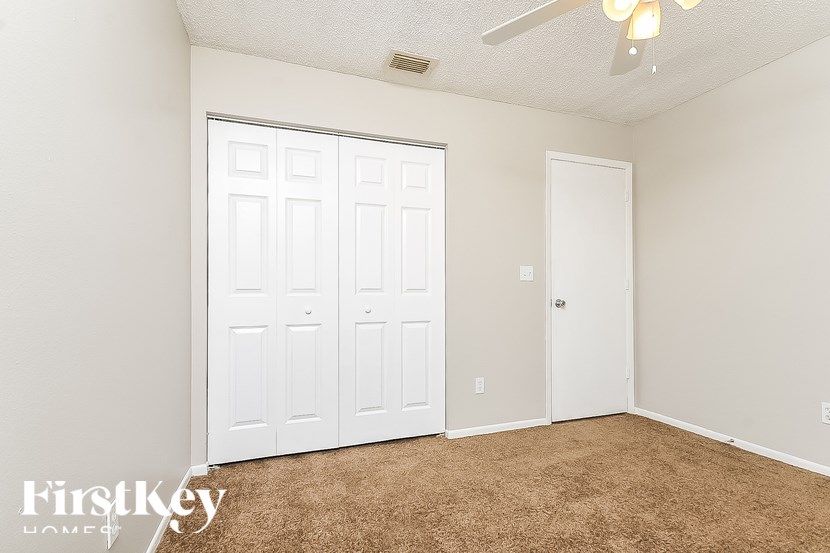 A room with a white door and a brown carpet.
