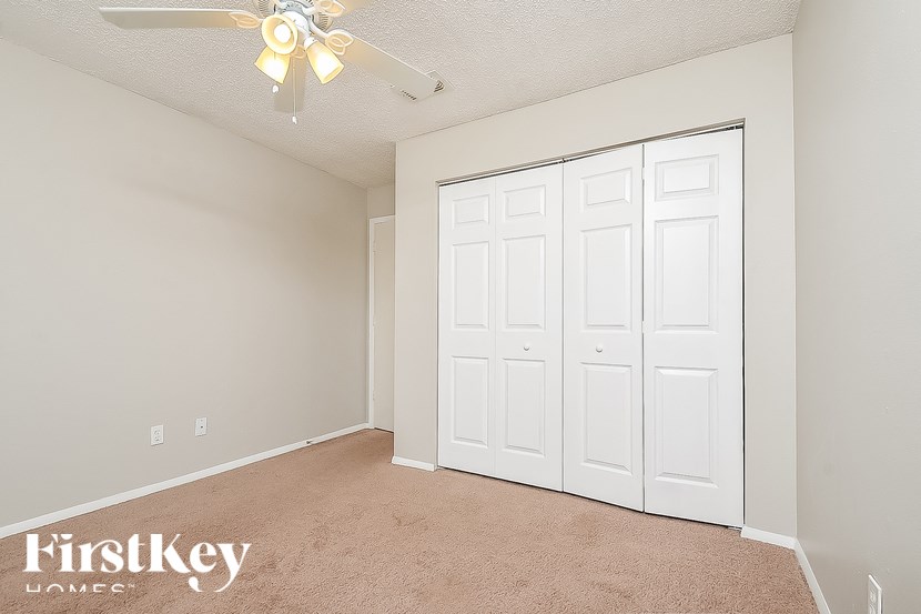 A room with a fan and a carpeted floor.