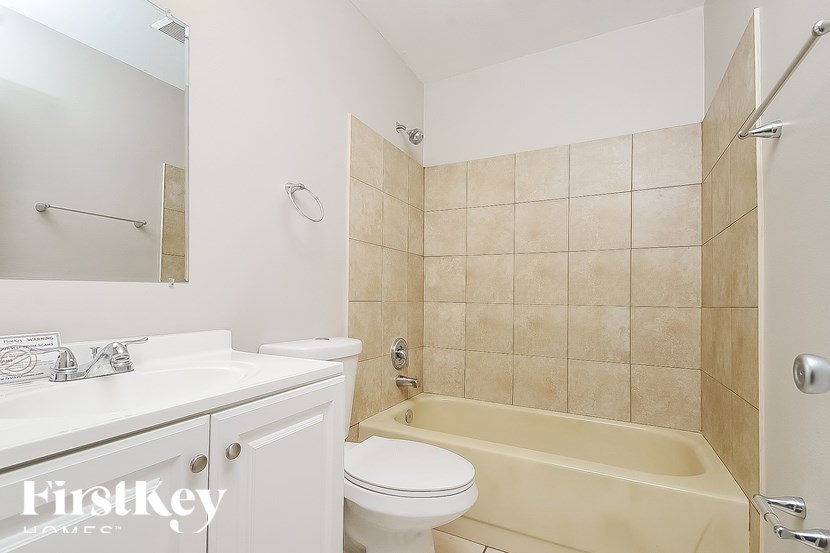 A white bathroom with a beige tiled shower.