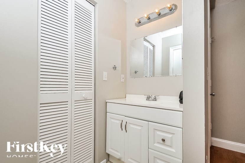 A white bathroom with a mirror and lights above it.