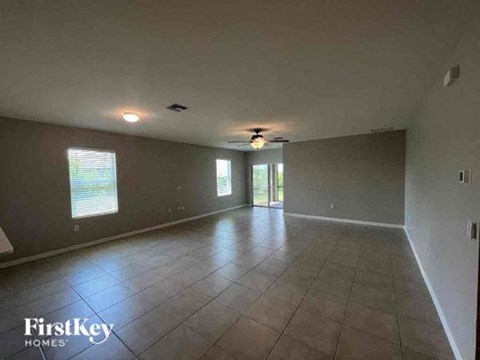 an empty living room with a ceiling fan and a tiled floor