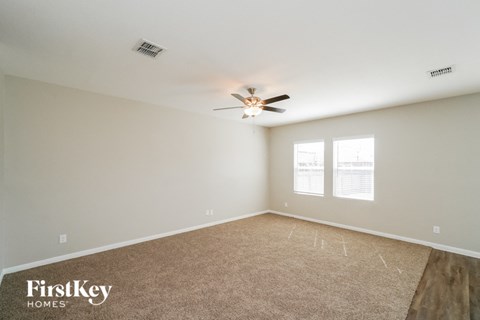 an empty living room with a ceiling fan and a window