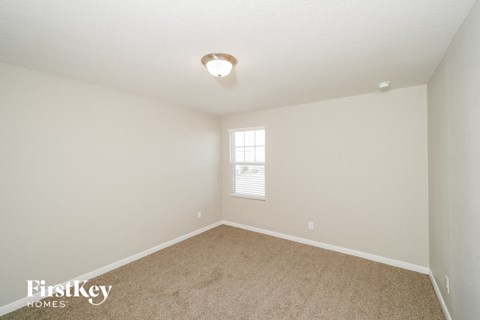 a bedroom with white walls and carpet and a window