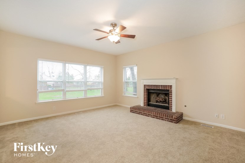 an empty living room with a fireplace and a ceiling fan
