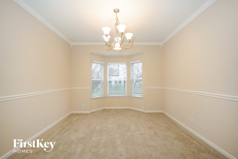 an empty dining room with a chandelier and a window