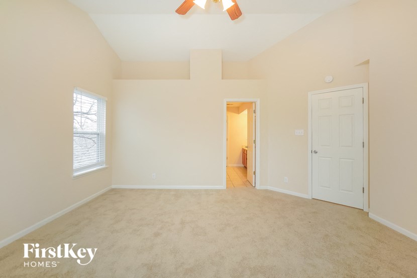 an empty living room with a white door and a ceiling fan