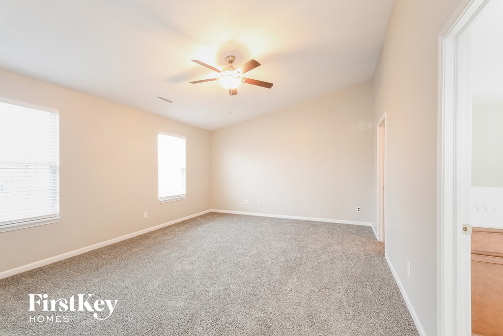 A room with a ceiling fan and carpeted floor.