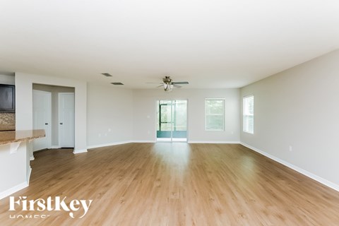 A spacious room with wooden flooring and a ceiling fan.