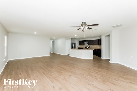 A spacious room with wooden flooring and a ceiling fan.