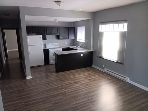 A kitchen with a white refrigerator and black countertops.