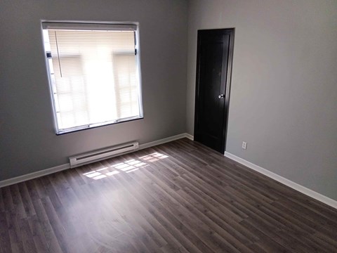 A room with a black door and a window with blinds.