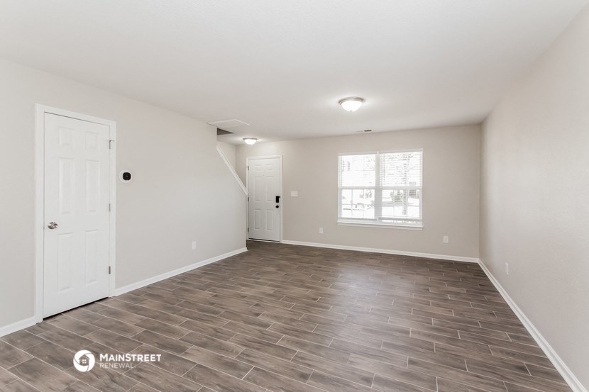 the spacious living room with vinyl flooring and white walls