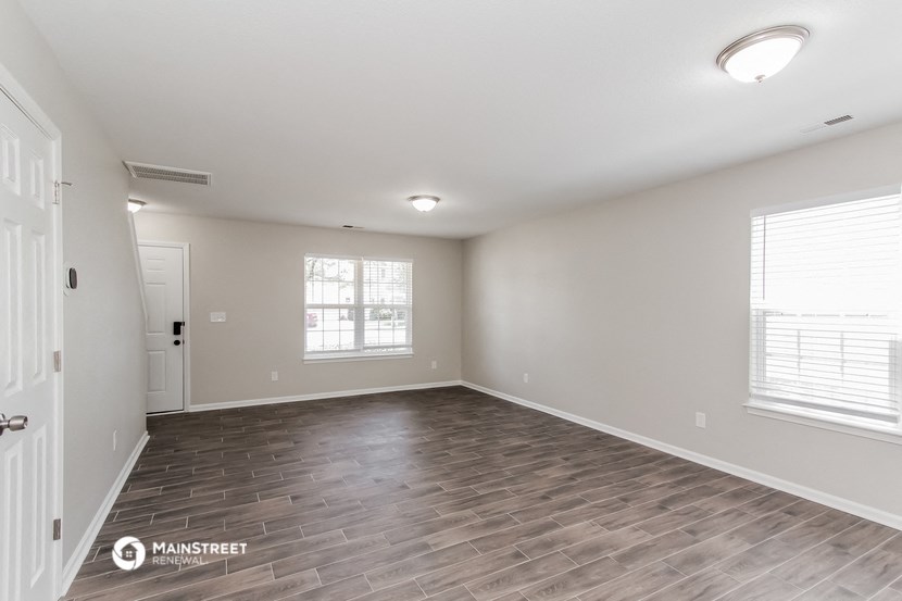 the spacious living room with wood flooring and white walls
