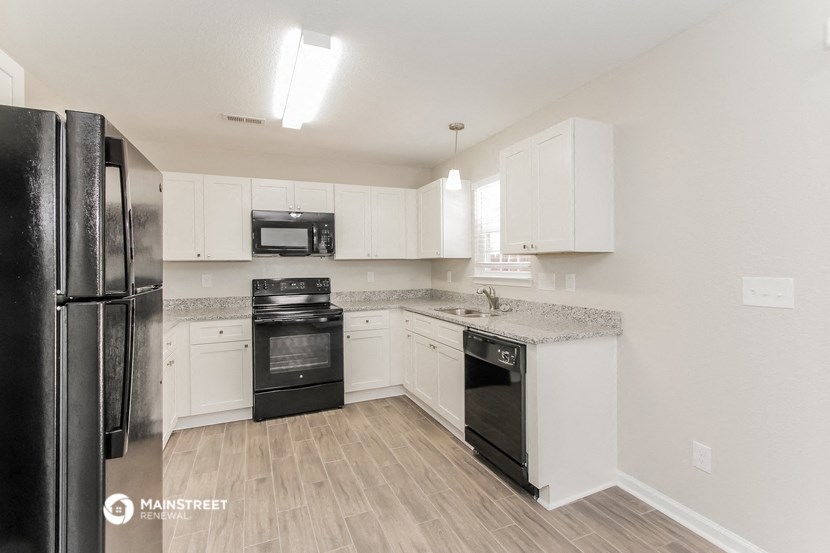 a renovated kitchen with white cabinets and black appliances
