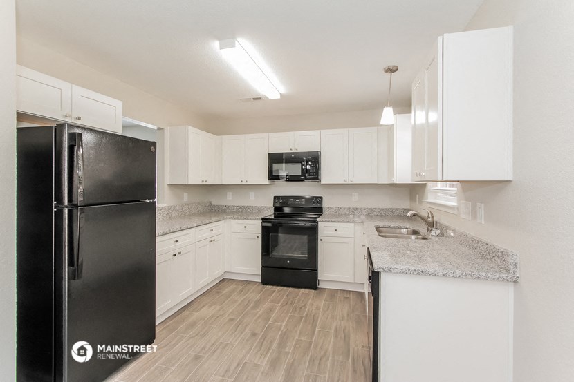 a kitchen with white cabinets and a black refrigerator