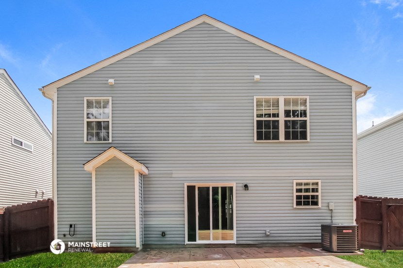 front view of a gray house with white siding and a wooden fence