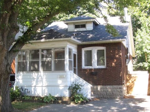 a red brick house with a tree in front of it