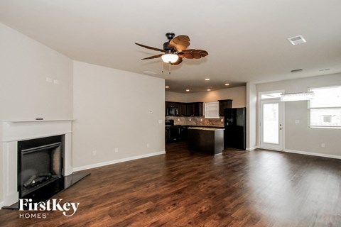 A spacious living room with a fireplace and a ceiling fan.