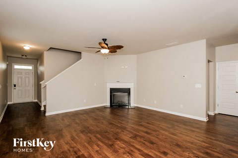 A spacious living room with a fireplace and a staircase.