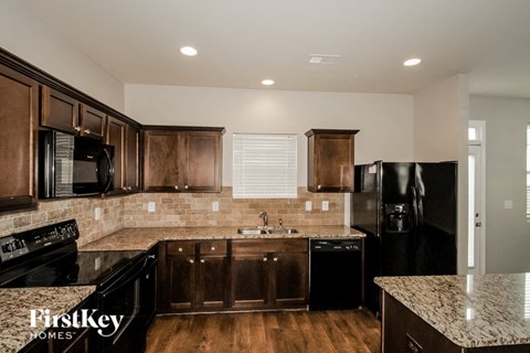 A kitchen with wooden cabinets and black appliances.