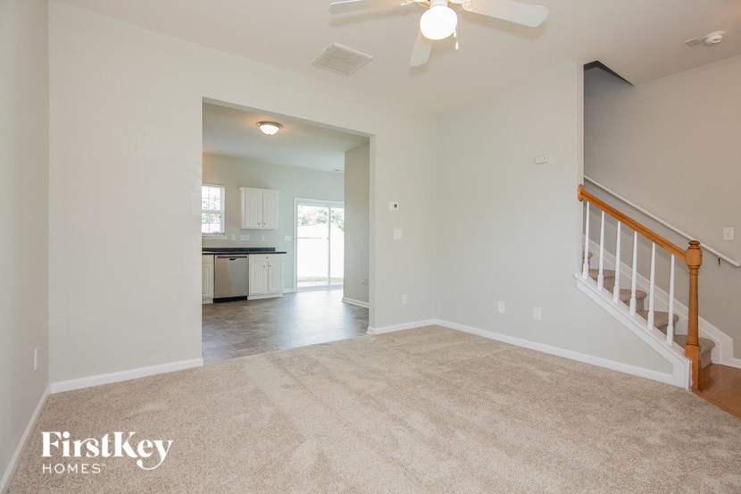 an empty living room with a staircase and a kitchen