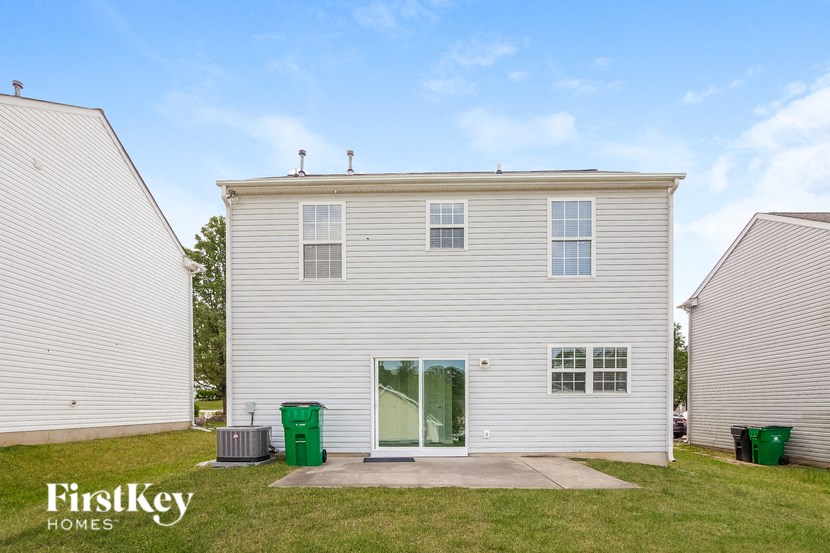 the exterior of a white house with green grass and a blue sky