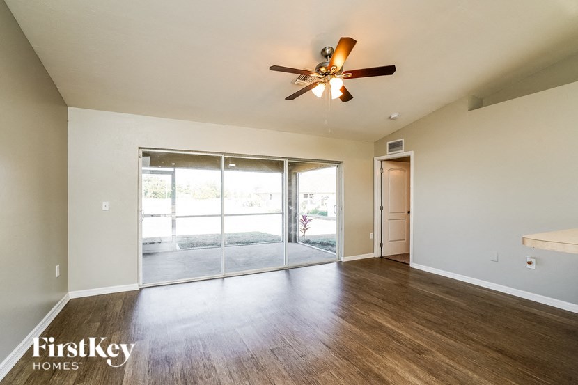 an empty living room with a ceiling fan and sliding glass doors