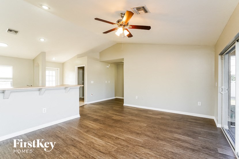 an empty living room and kitchen with a ceiling fan