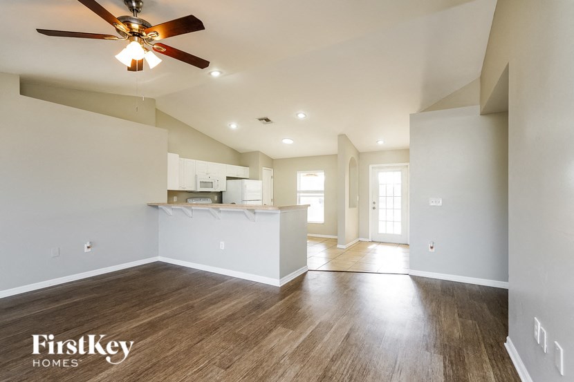 an empty living room and kitchen with a ceiling fan