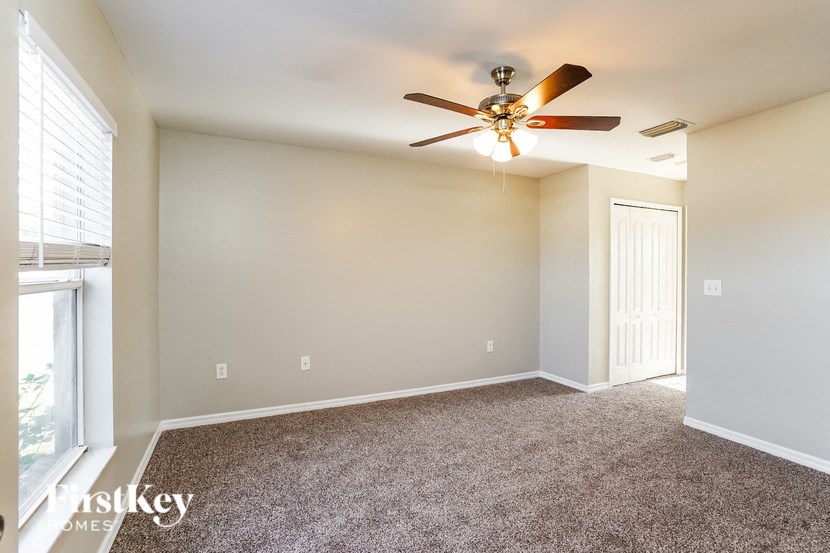 an empty living room with a ceiling fan and a window