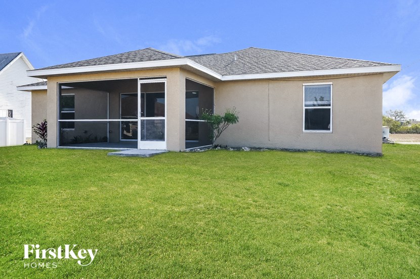 a beige house with a grass yard and a patio