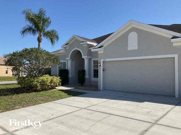 a white house with a garage door and a palm tree