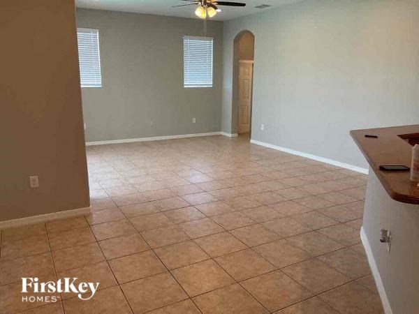 an empty living room with a tile floor and a ceiling fan